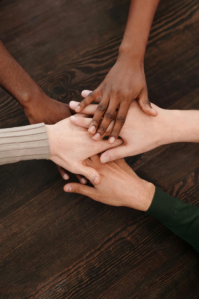 Close-up of diverse hands stacked together on wooden surface symbolizing teamwork and unity.